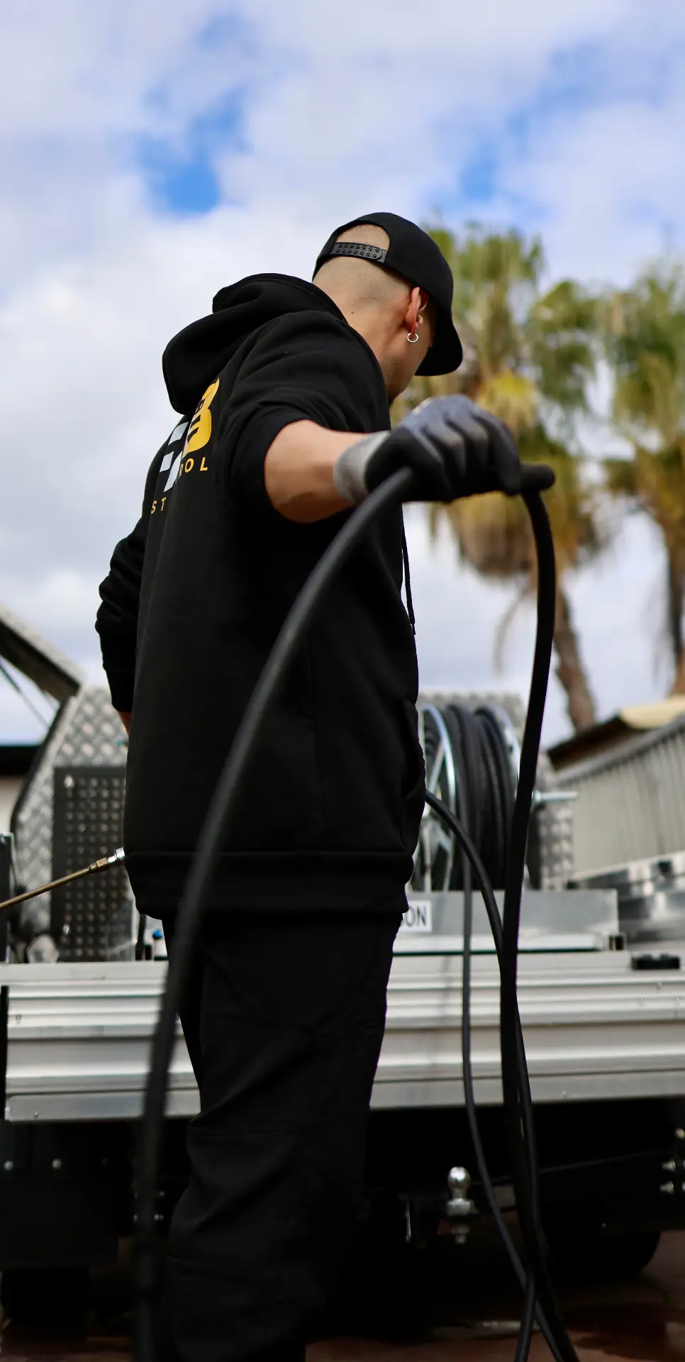 Fabien, FAB Pest Control's founder, preparing equipment at the back of his service vehicle outside a Perth home.